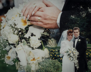 A creative double-exposure wedding photograph by High-Tech Studios in Pasadena, showing a close-up of hands with gold wedding rings over white roses, blended with a classic wedding portrait.